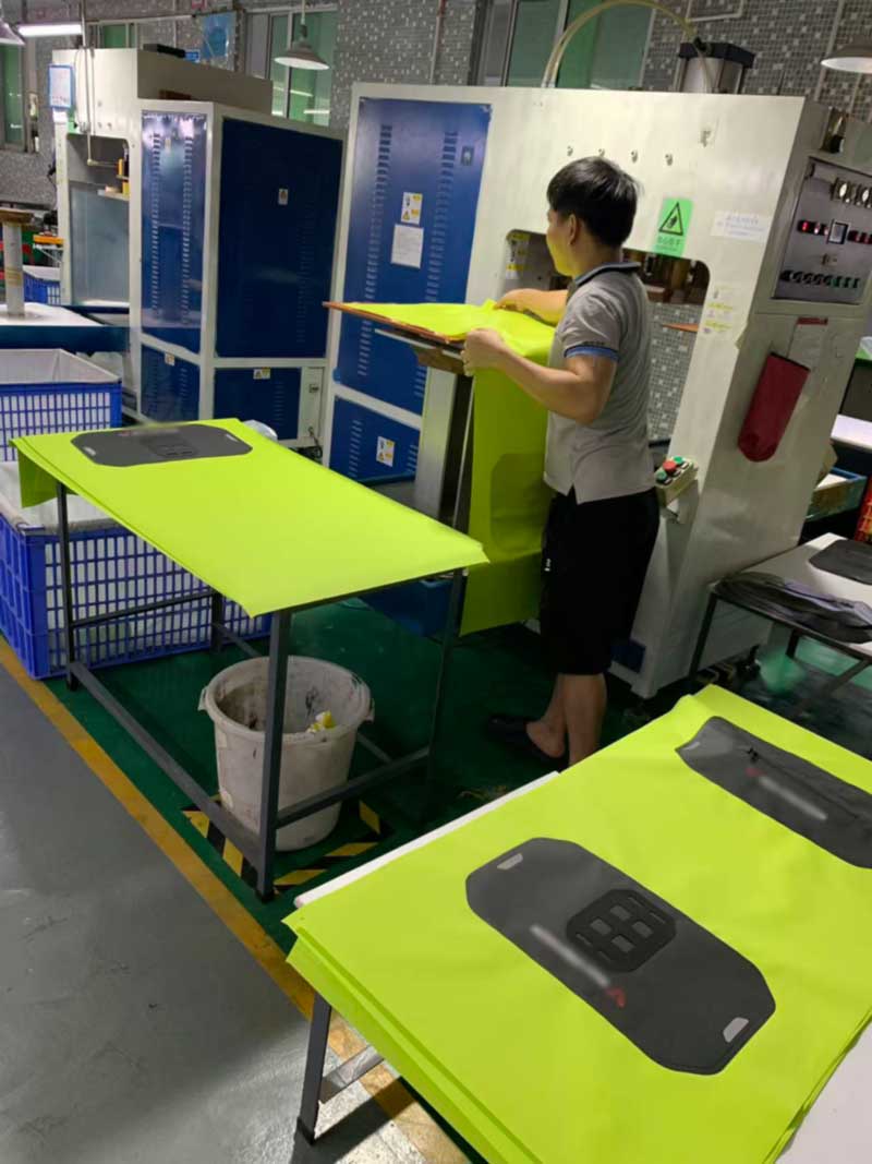 Operator positioning fluorescent waterproof fabric on a high-frequency welding machine